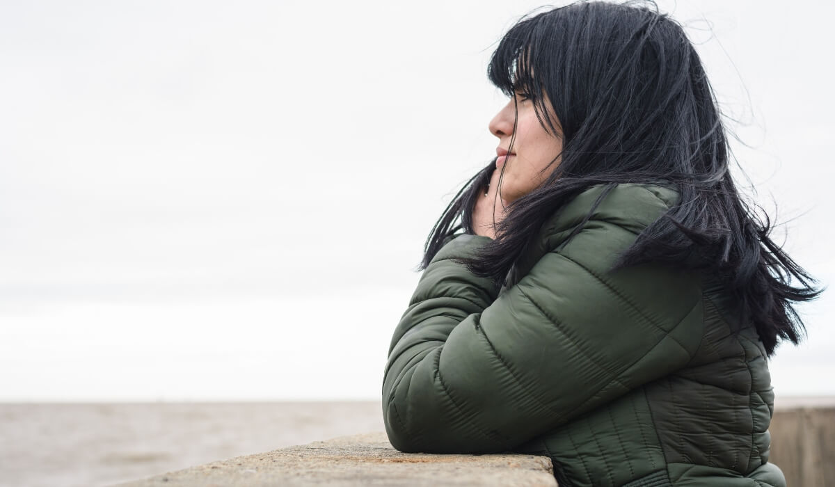 A woman looks over the water reflecting emotional challenges linked to infertility depression.